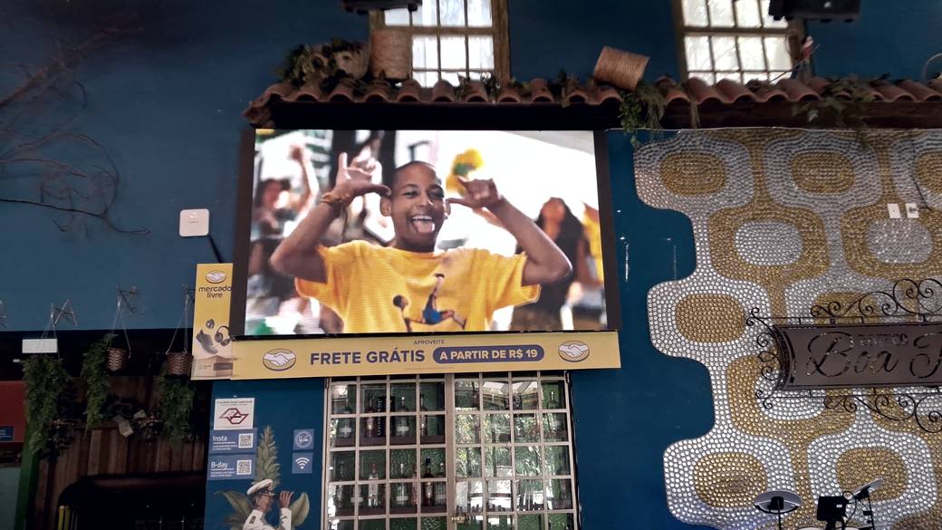 Faixa estática de marca instalada na base do telão de um bar