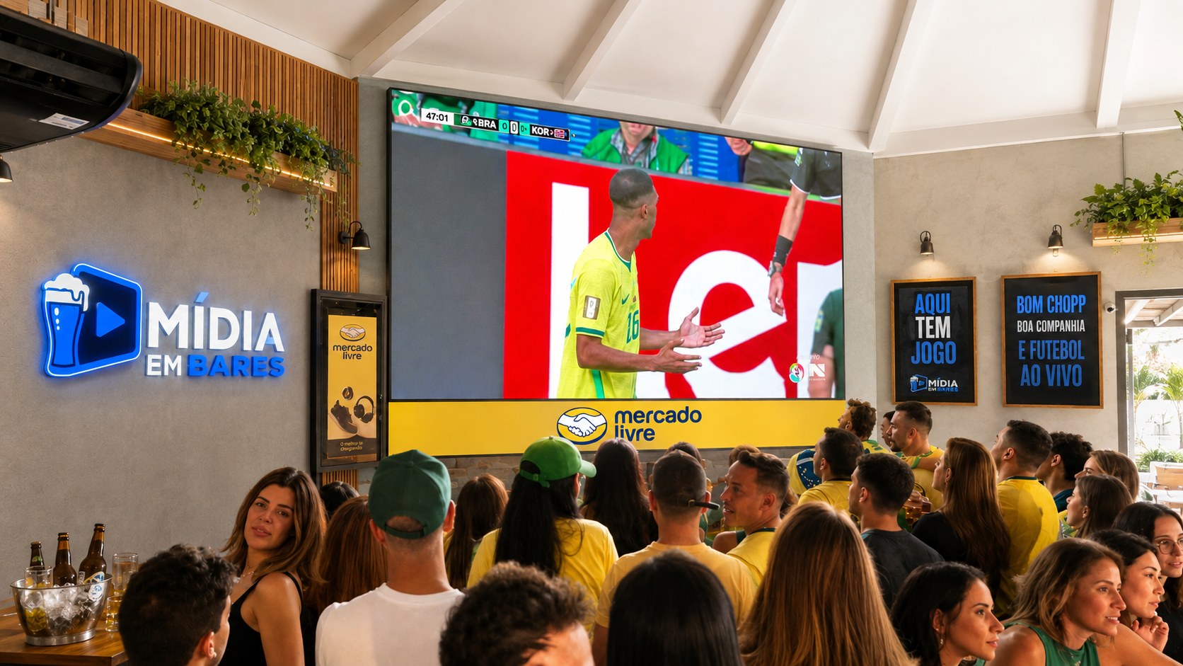 Bar lotado: a torcida de costas assiste ao jogo num telão de LED, ao lado
              de um letreiro luminoso com a marca Mídia em Bares